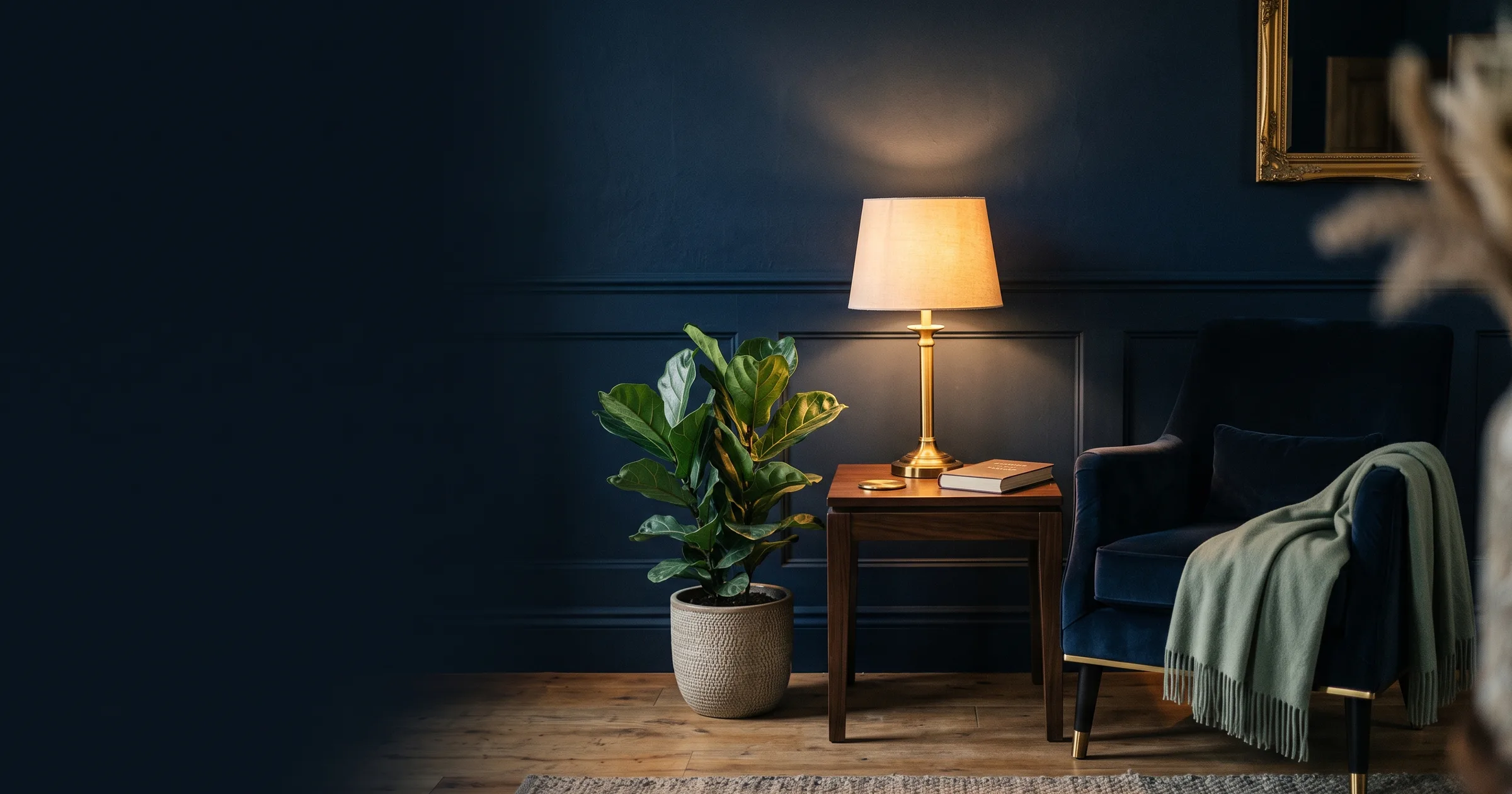 Boutique hotel guest lounge with sage plant, brass lamp, and navy armchair
